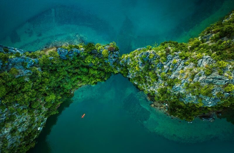 Drone view on rocks and canoes floating on turquoise water in the Halong Bay